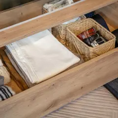 Jak zorganizować szafę? W szufladzie schludnie poukładane ubrania, paski w wiklinowym koszyku.