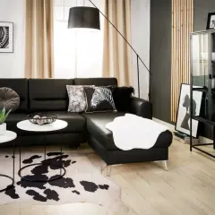 Nowoczesny salon z czarną sofą, dywanem w cętki i czarną ścianą inspiracje.