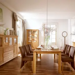 Nowoczesny salon ze starymi meblami z litego drewna. Dębowe komody i witryny tworzą ciepłą atmosferę, a skórzane krzesła dodają elegancji.