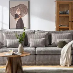Miękka, sztruksowa kanapa a sofa w salonie, z poduszkami i kocem, obok stolika kawowego i obrazu.