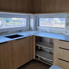 Nowoczesny parapet w kuchni nad blatem z marmurowym wykończeniem i drewnianymi frontami szafek.