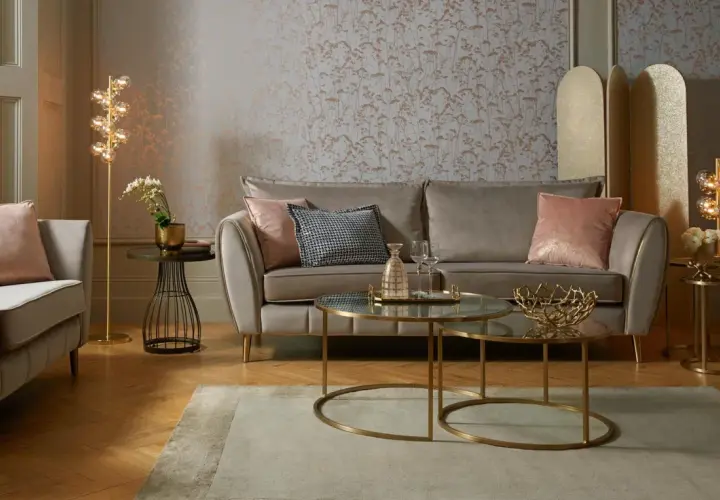 Przytulny salon glamour z beżową sofą, różowymi poduszkami i złotymi dodatkami.