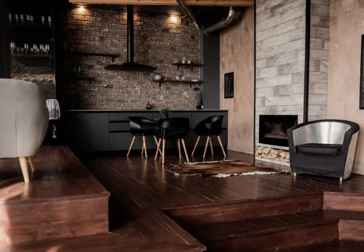 Nowoczesny salon z ciemną podłogą, ceglaną ścianą i designerskimi meblami.