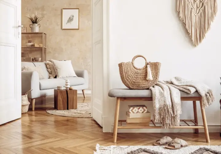 Przytulny salon w stylu boho. Jasna kanapa, pleciona torba i makrama tworzą relaksującą atmosferę.