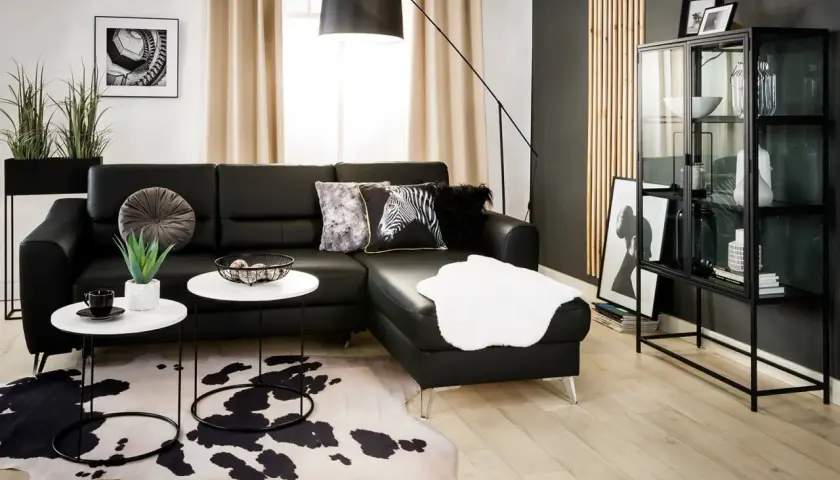 Nowoczesny salon z czarną sofą, dywanem w cętki i czarną ścianą inspiracje.