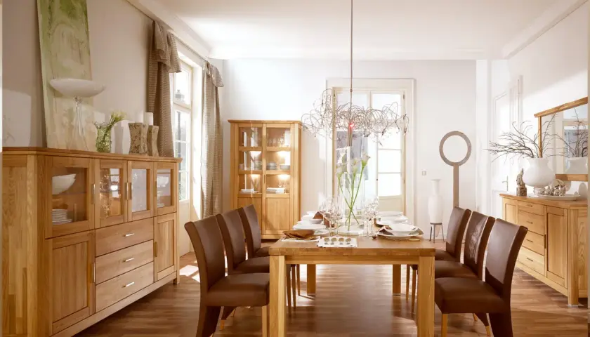 Nowoczesny salon ze starymi meblami z litego drewna. Dębowe komody i witryny tworzą ciepłą atmosferę, a skórzane krzesła dodają elegancji.