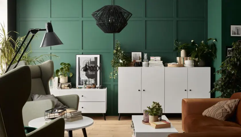 Zieleń ścian pięknie komponuje się z brązową sofą i zielonymi fotelami. Wnętrze z elementami boho i nowoczesnymi.