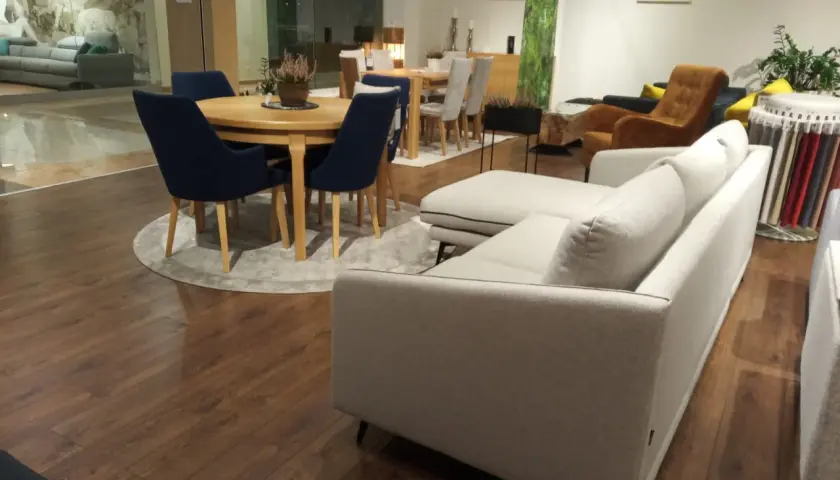 Nowoczesna aranżacja salonu z szarą kanapą i granatowymi krzesłami przy okrągłym stole. Czy krzesła muszą być w kolorze kanapy?