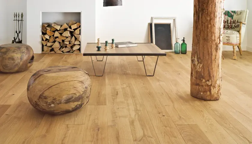 Salon w stylu francuskim inspiracje: drewniane pnie, kominek z polanami, stolik kawowy i fotel z worka.