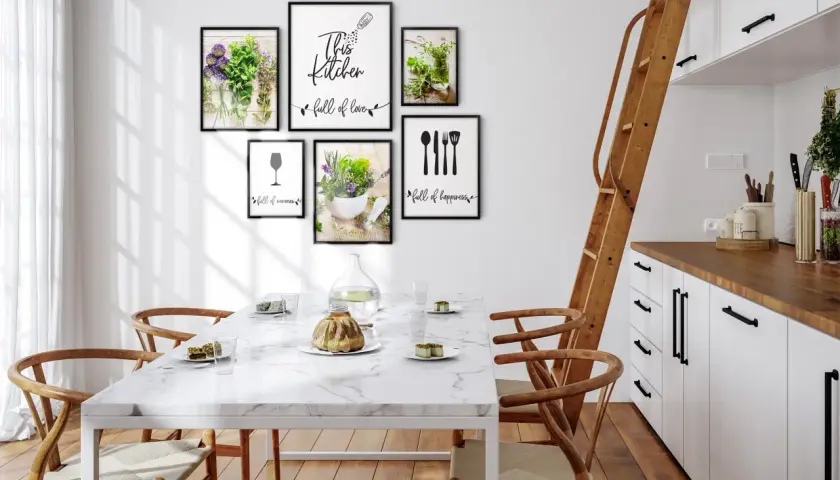 Pusta ściana w kuchni ozdobiona ramkami z motywami roślinnymi i kuchennymi. "This kitchen full of love" - napis na jednej z nich.