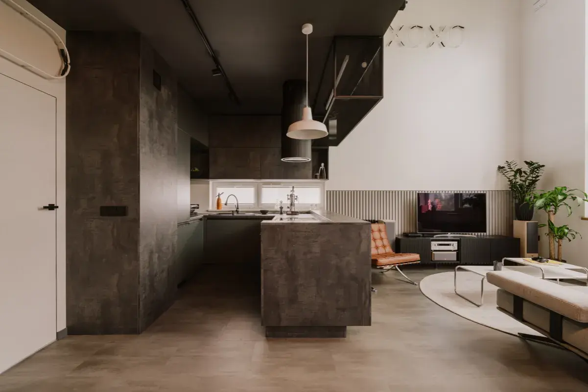 Nowoczesna kuchnia i salon w stylu eco brutalism. Betonowe powierzchnie, ciemne akcenty i minimalistyczne meble tworzą surowy, ale przytulny klimat.