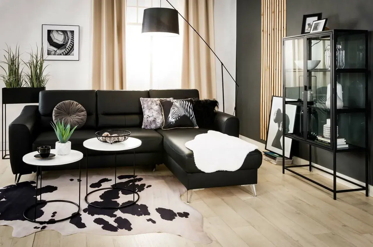 Nowoczesny salon z czarną sofą, dywanem w cętki i czarną ścianą inspiracje.