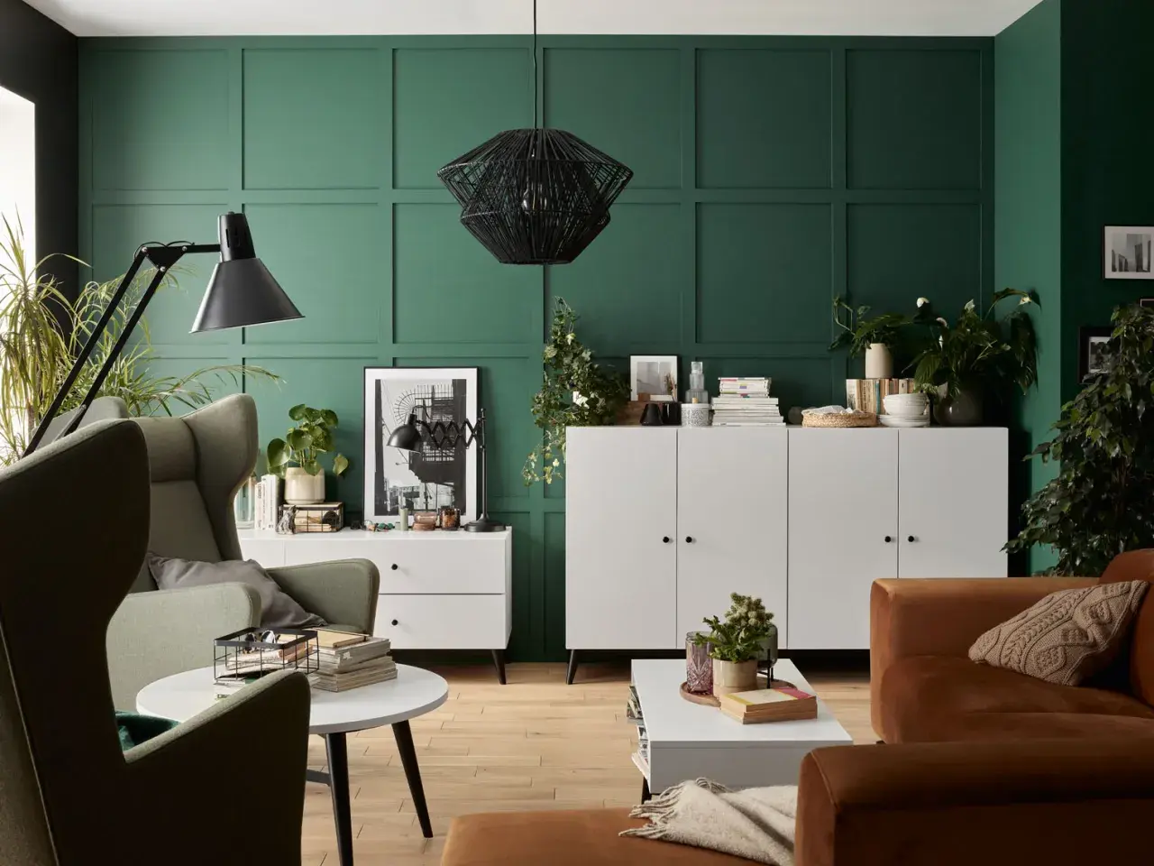 Zieleń ścian pięknie komponuje się z brązową sofą i zielonymi fotelami. Wnętrze z elementami boho i nowoczesnymi.