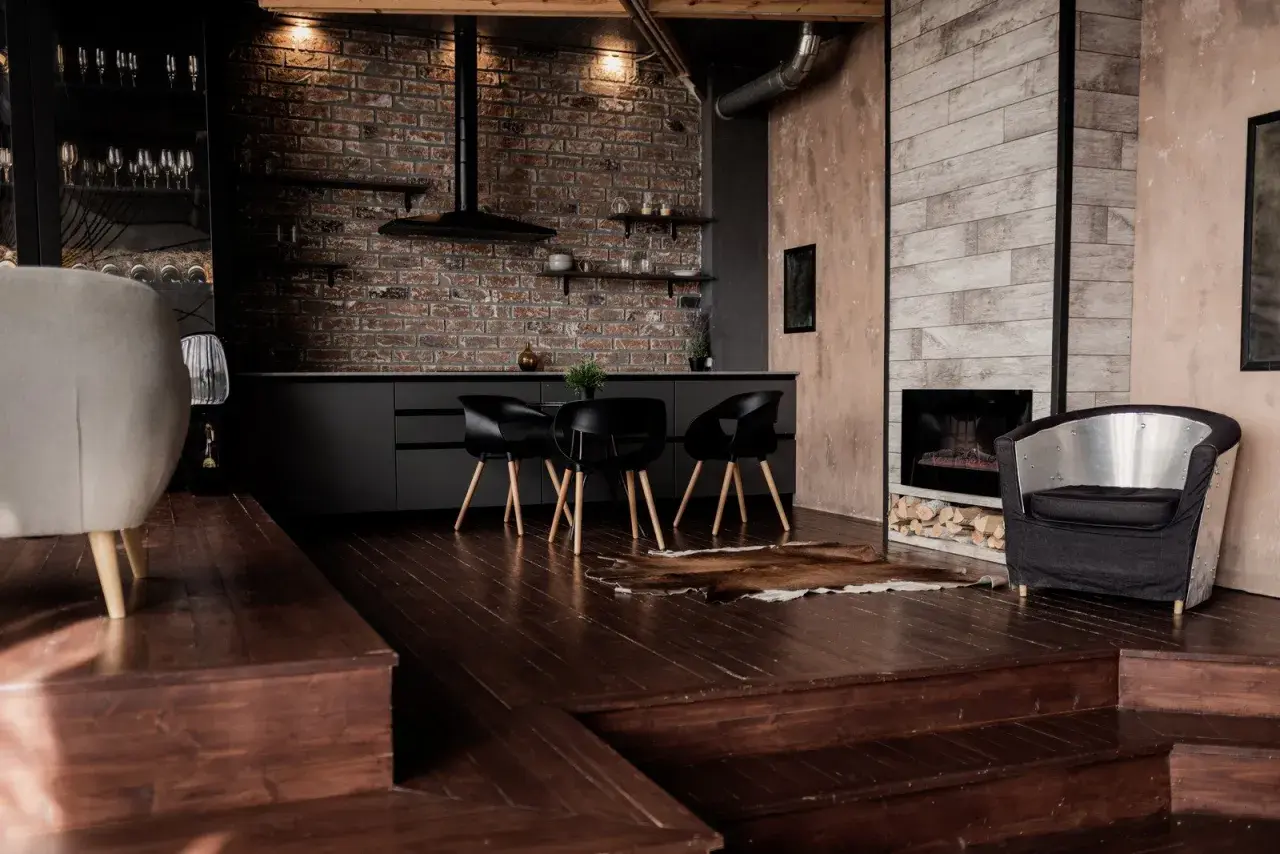 Nowoczesny salon z ciemną podłogą, ceglaną ścianą i designerskimi meblami.