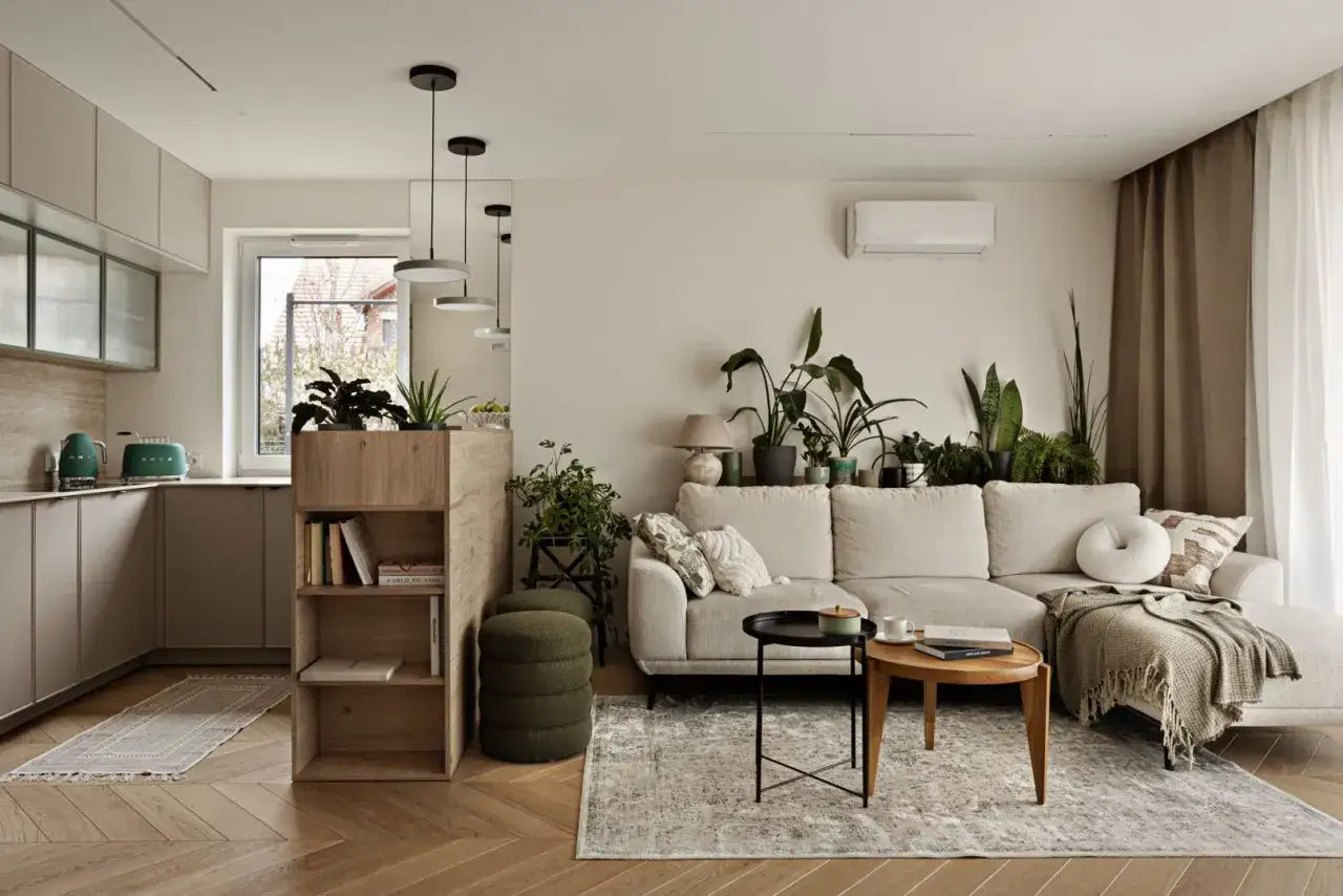 Przytulny salon nowoczesny z dużą ilością zieleni. Jasna kanapa, drewniane meble i stylowe dodatki tworzą relaksującą atmosferę.