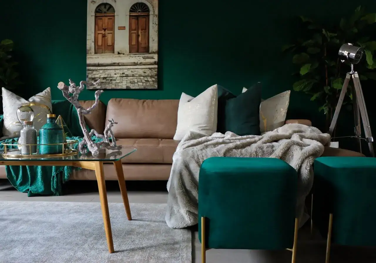 Elegancki salon z brązową kanapą, zielonymi akcentami i złotymi dodatkami. Zobacz, z czym łączyć zieleń, by stworzyć przytulną atmosferę.