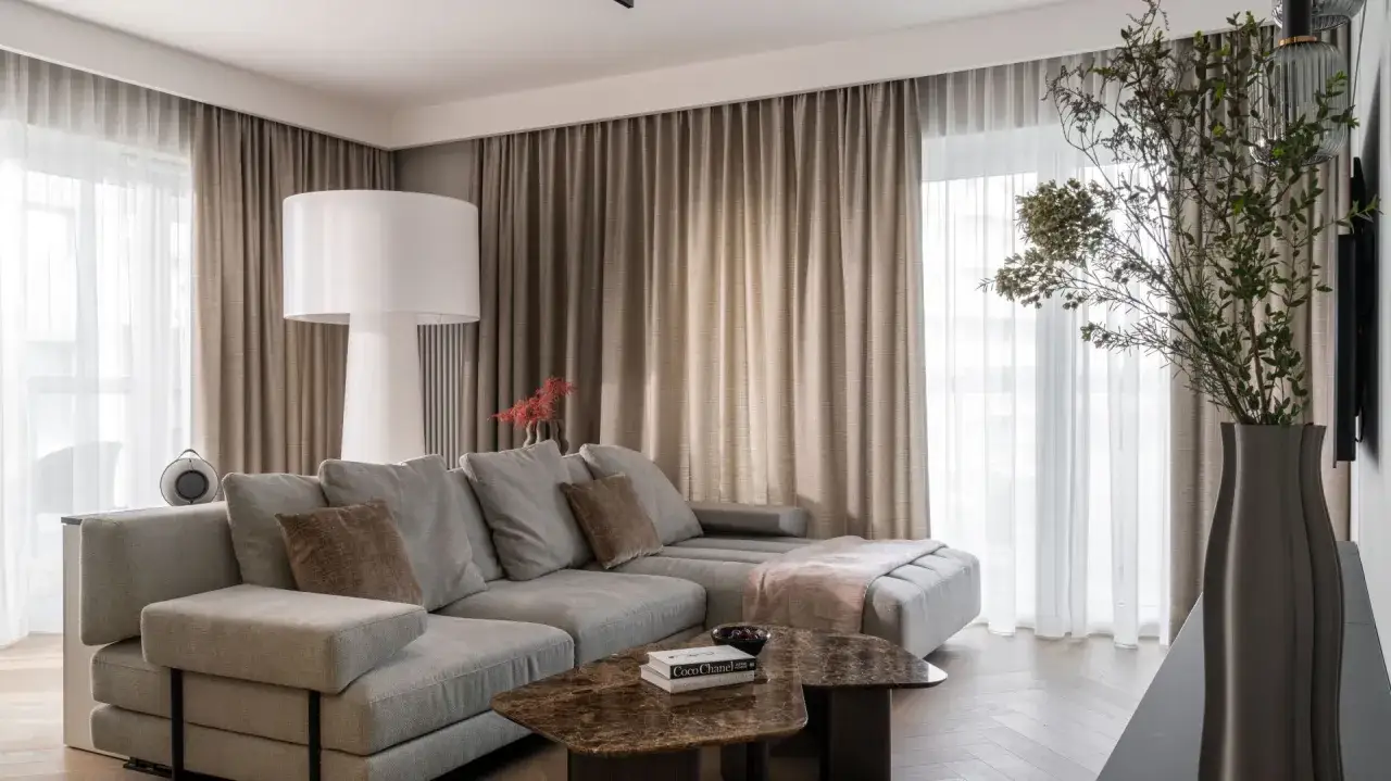 Elegancki salon z szarą kanapą i brązowymi zasłonami. Dowiedz się, jak dobrać zasłony do koloru ścian, by stworzyć harmonijną przestrzeń.