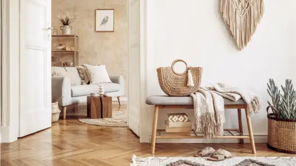 Przytulny salon w stylu boho. Jasna kanapa, pleciona torba i makrama tworzą relaksującą atmosferę.